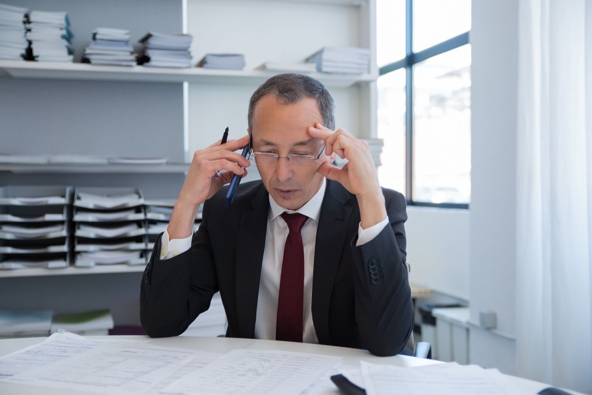 Angespannter Unternehmer mittleren Alters bei einem Telefonat